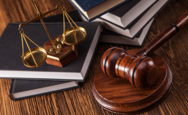 Legal books, scales of justice, and a gavel on a wooden table.