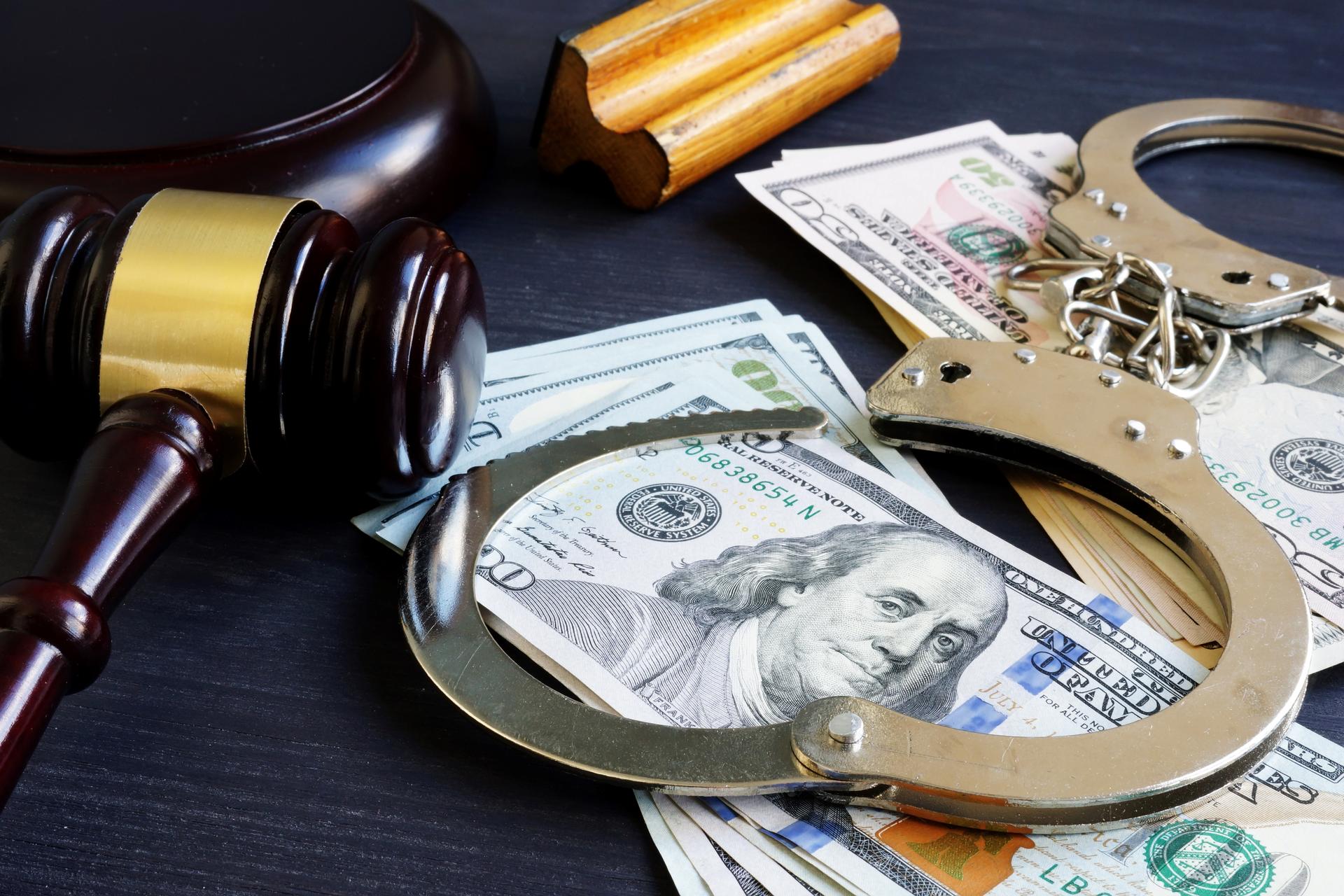 Gavel, cash, and handcuffs on table
