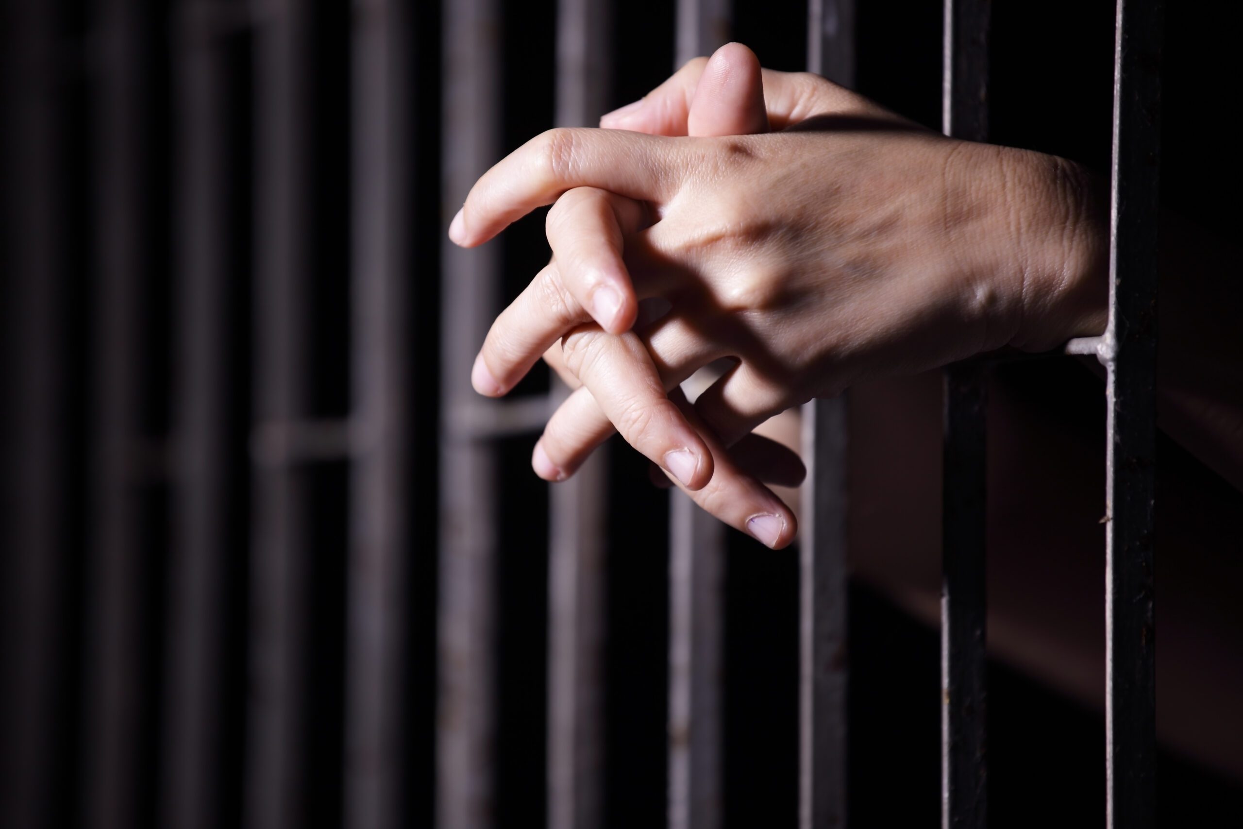 Fingers intertwined through jail bars
