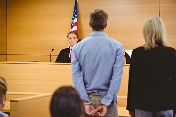 Defendant stands handcuffed in front of judge